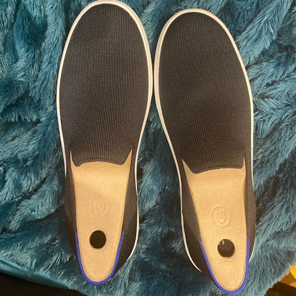 Rothy’s black sneakers with white and blue strip.